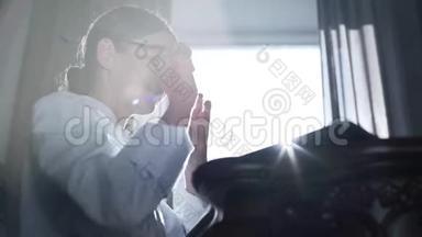 职业女医生戴着眼镜在笔记本电脑上打字，坐在<strong>靠窗</strong>的<strong>桌子</strong>旁